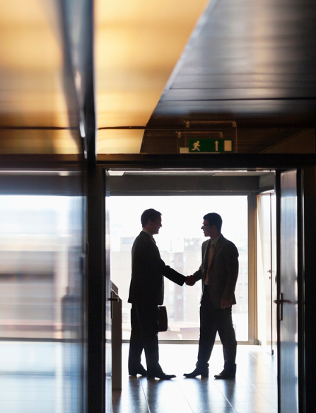 Businessman shaking hands together in corridor